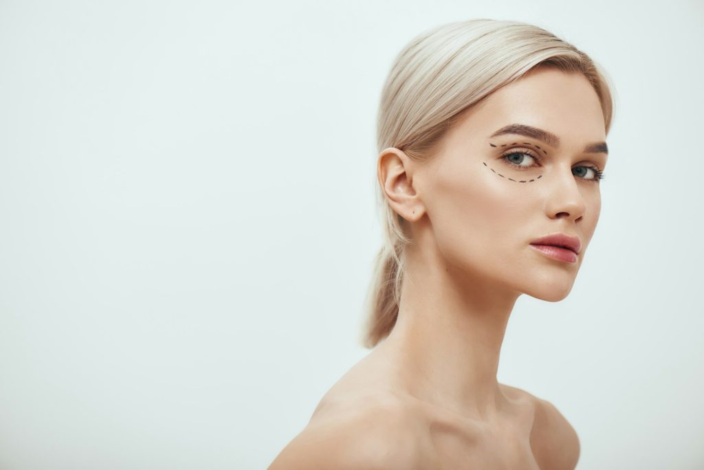 Beautiful and young blonde woman with black surgical lines on eyelids