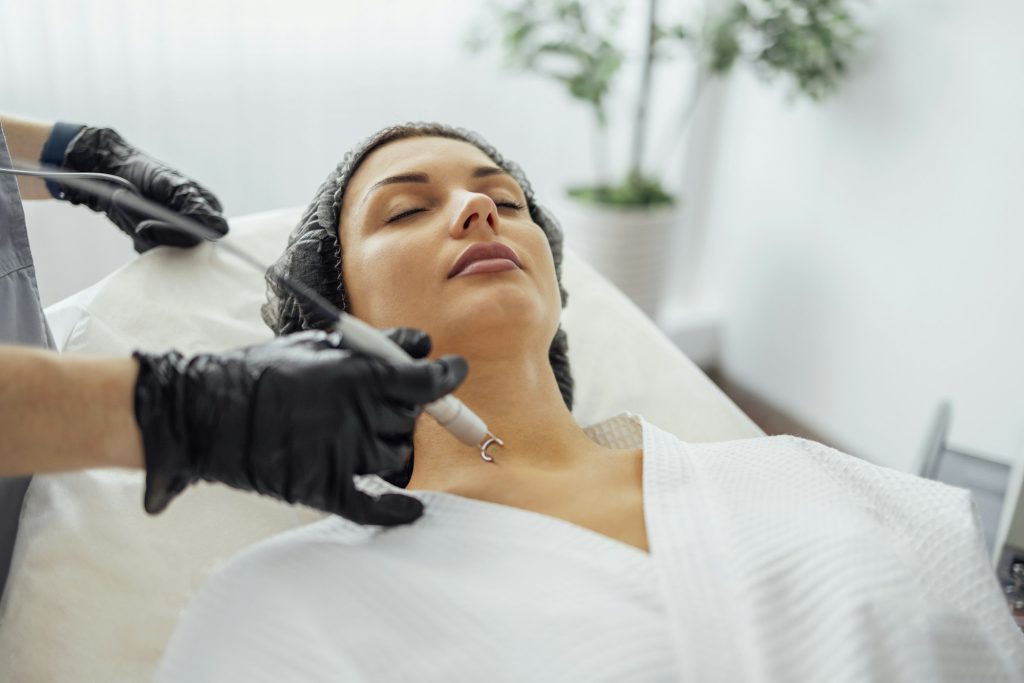 Beautiful caucasian young woman is doing a mole removal procedure in a modern beauty cosmetic clinic
