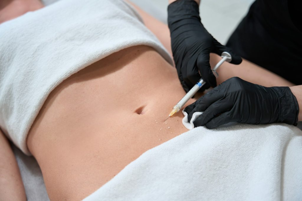 Female in black gloves makes injections in belly of client
